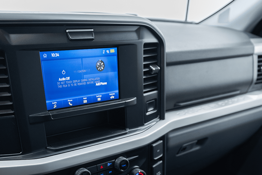 Close-up of a Demers ambulance cab infotainment display integrated into the dashboard, showing the touchscreen interface with audio and system controls positioned beside the center air vents