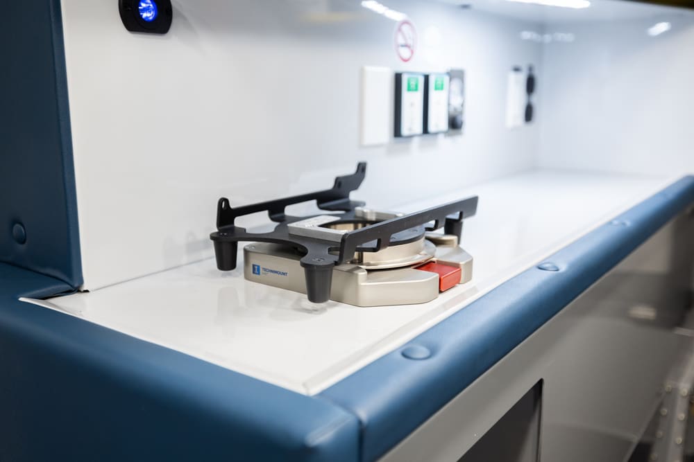 Close-up of a Demers ambulance work surface with a securely mounted equipment base on a smooth, easy-to-clean countertop, designed for stable device placement and efficient clinical workflow