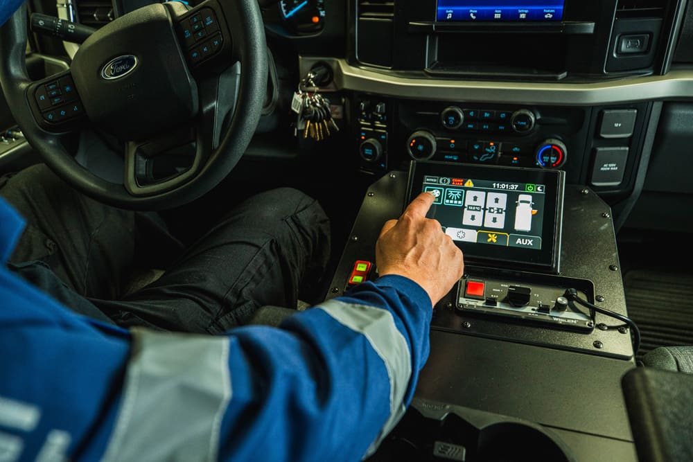 Driver interacting with a Demers ambulance cab touchscreen control panel, managing vehicle and patient compartment systems from an integrated, in-cab interface