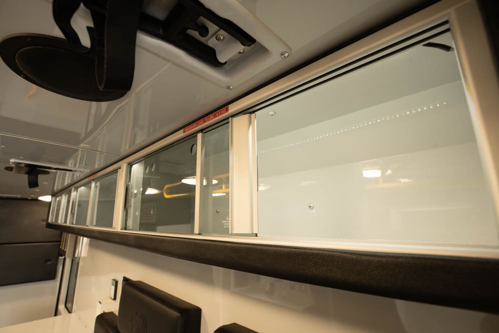 Overhead glass-front storage cabinets inside a Demers ambulance, providing clear visibility and secure organization of medical supplies within the patient compartment
