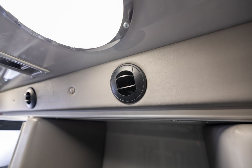 Close-up of an adjustable circular air vent integrated into the Demers ambulance patient compartment wall beneath ceiling lighting, supporting targeted airflow and climate control