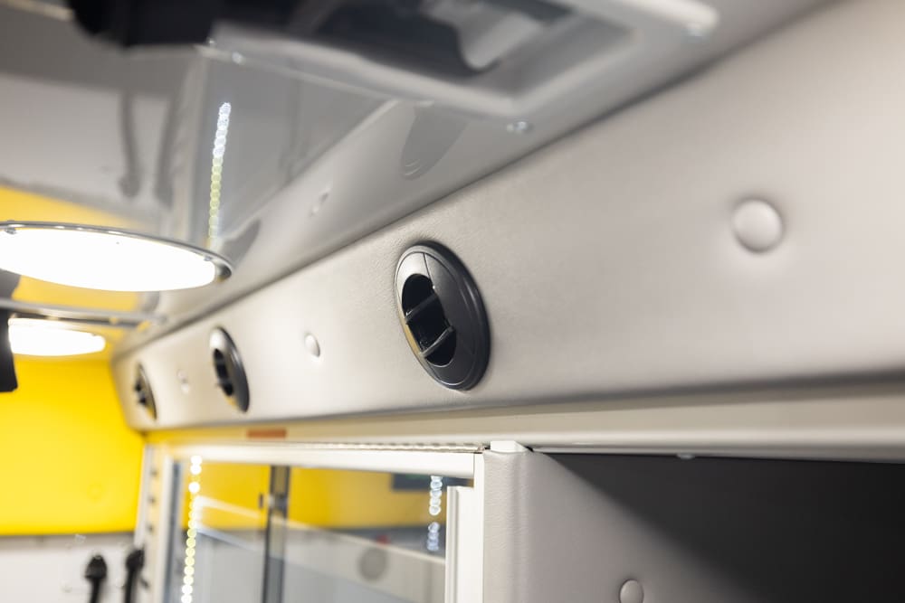 Close-up of adjustable air vents integrated into the Demers ambulance patient compartment cabinetry, supporting targeted airflow and climate control above storage cabinets