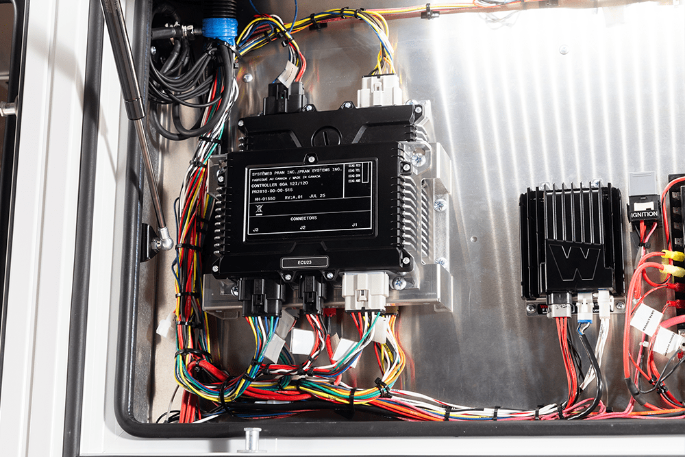 Close-up of a Demers ambulance electrical control module with labeled ECU unit, organized wiring harnesses, and mounted ignition components inside an aluminum compartment