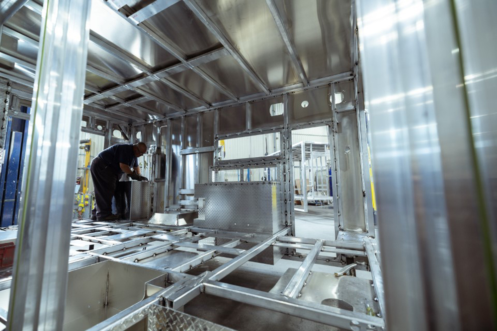 Inside shot of aluminum ambulance module frame with welder working to integrate cabinetry.